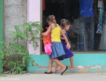 These girls play and dance on the sidewalk while they follow their mother on her errands.